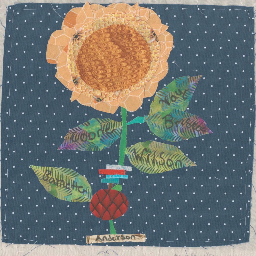 A quilt square depicting a large flower growing in a pot