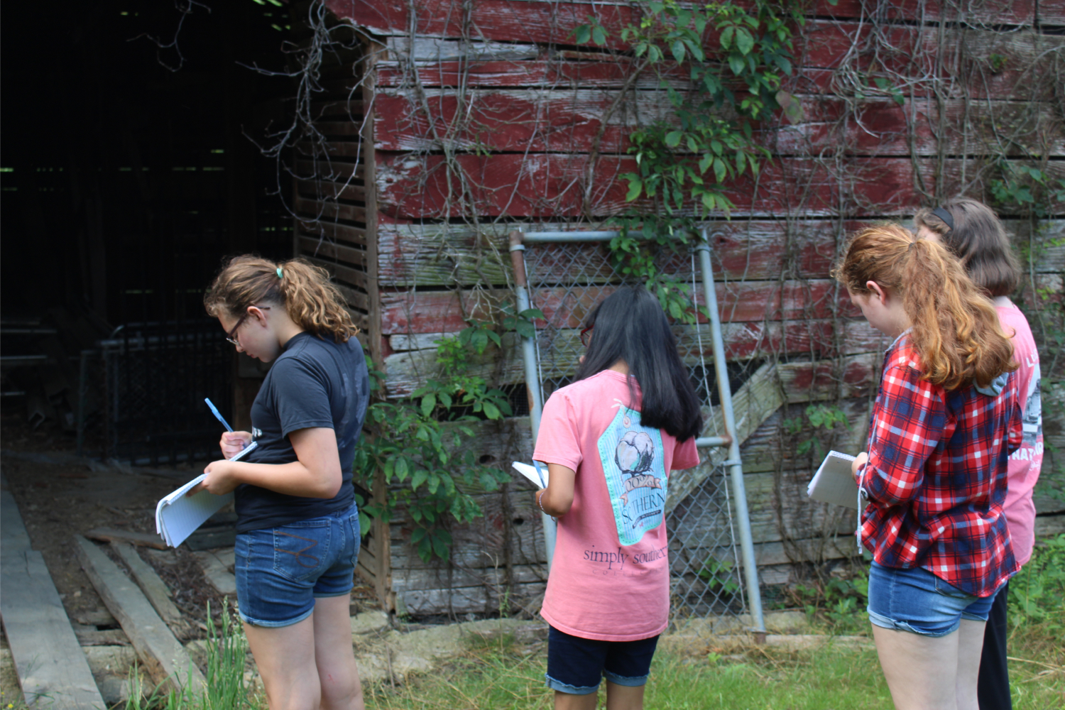 3 PAGE girls writing notes while standing outside a weathered barn