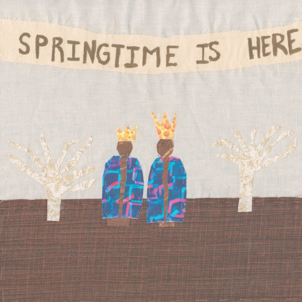 A quilt square with a banner at the top reading "Springtime is here". Two African American figures are dressed in colorful blue robes. They wear crowns. Bare trees are to the left and right of them. The ground is brown.